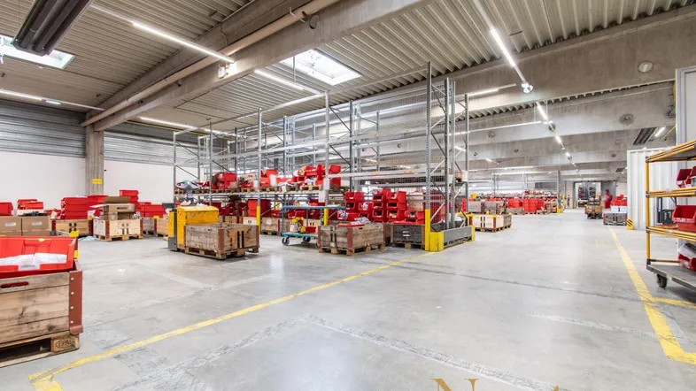 Geräumige Lagerhalle mit hohen Decken, Oberlichtern und Regalsystemen für industrielle Nutzung.
