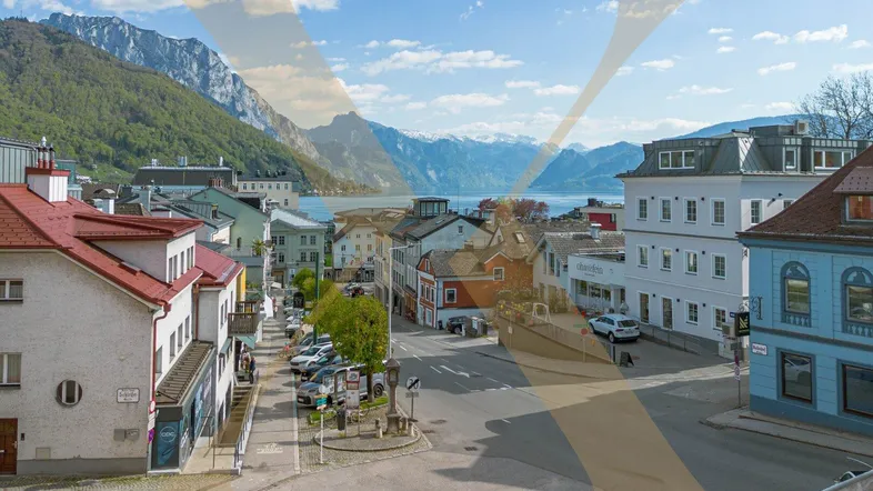 Panoramablick auf die malerische Stadt am See mit umliegenden Bergen und blauem Himmel.