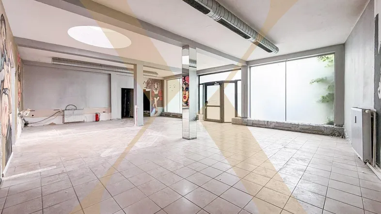 Großer, offener Gewerberaum mit Fliesenboden, hohen Decken und großen Fenstern, ideal für Ladenlokal oder Büro.