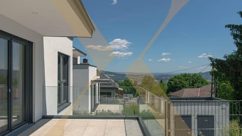 Große Terrasse mit Fliesenboden, Glasgeländer und weitem Blick über die Landschaft.