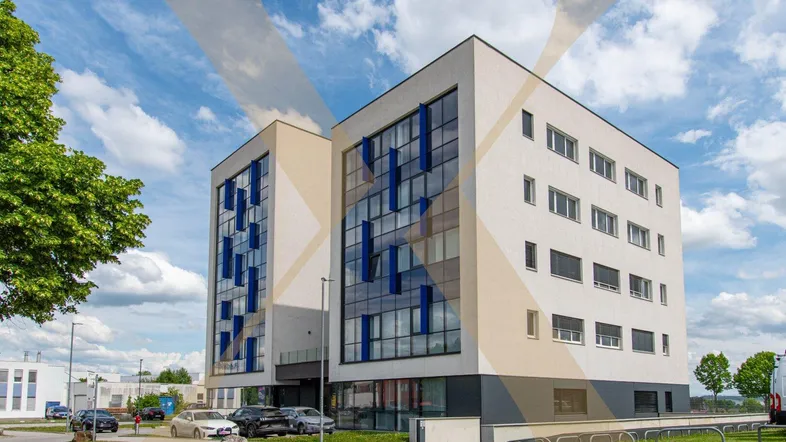 Modernes Bürogebäude mit weißer Fassade und großen Fenstern unter blauem Himmel.
