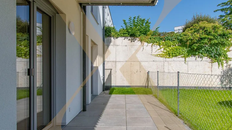 Gepflasterte Terrasse mit Zugang zum Garten und einer grünen Wandbegrünung in sonniger Lage.