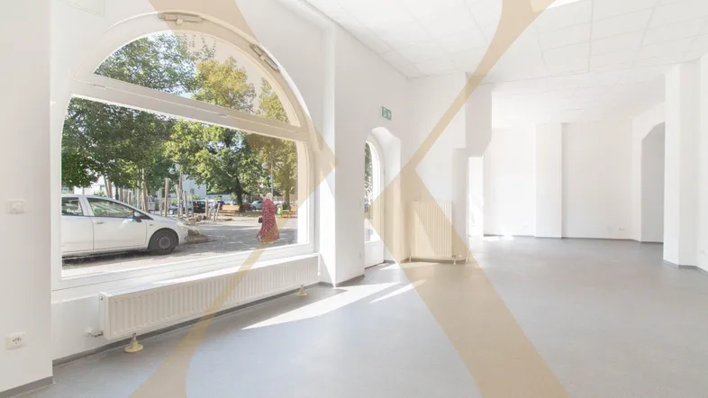 Heller, leerer Gewerberaum mit großen Rundbogenfenstern und Blick auf die Straße.