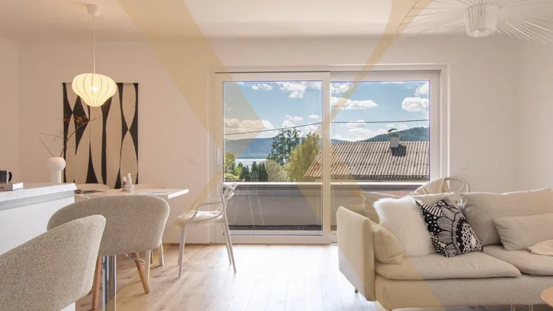 Heller Wohn- und Essbereich mit Holzboden, Seeblick und Zugang zum Balkon.