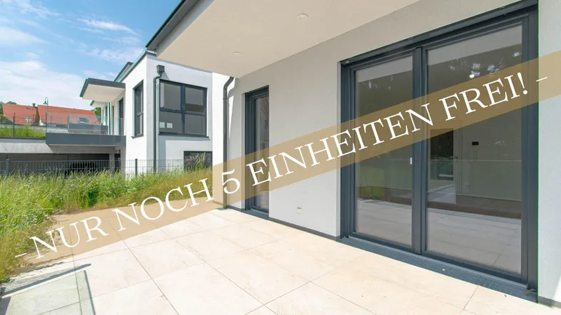 Moderne Neubauwohnung mit großer gefliester Terrasse und Zugang zum grünen Gartenbereich.