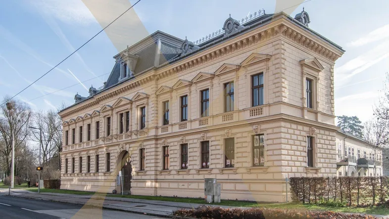 Eindrucksvolles historisches Gebäude mit klassizistischer Fassade und Mansarddach, gelegen an einer städtischen Straße.