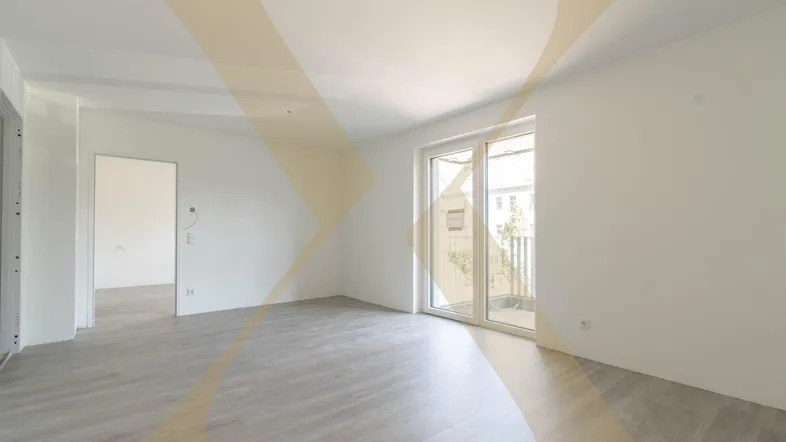 Heller, leerer Wohnraum mit modernem Laminatboden und Zugang zu einem Balkon.