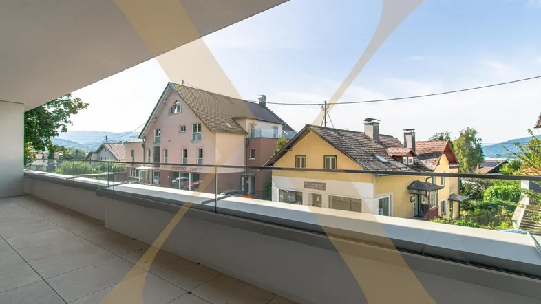 Geräumiger Balkon mit Fliesenboden und Glasgeländer, bietet einen weiten Blick auf die Umgebung.