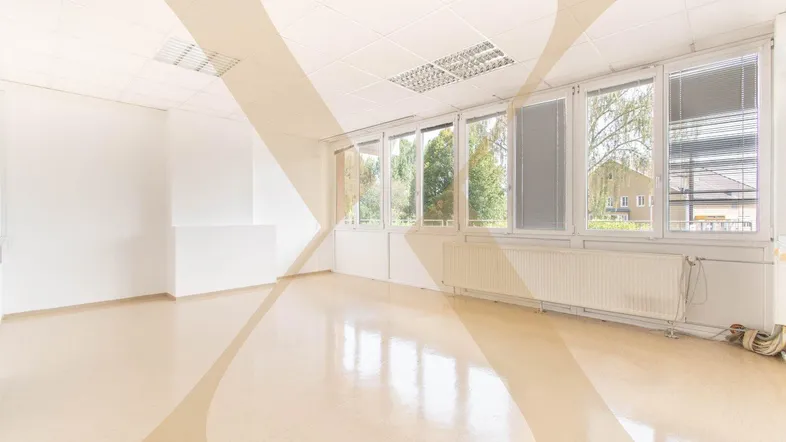 Heller Büroraum mit großen Fenstern, die viel Tageslicht hereinlassen und einem funktionalen Deckenraster.