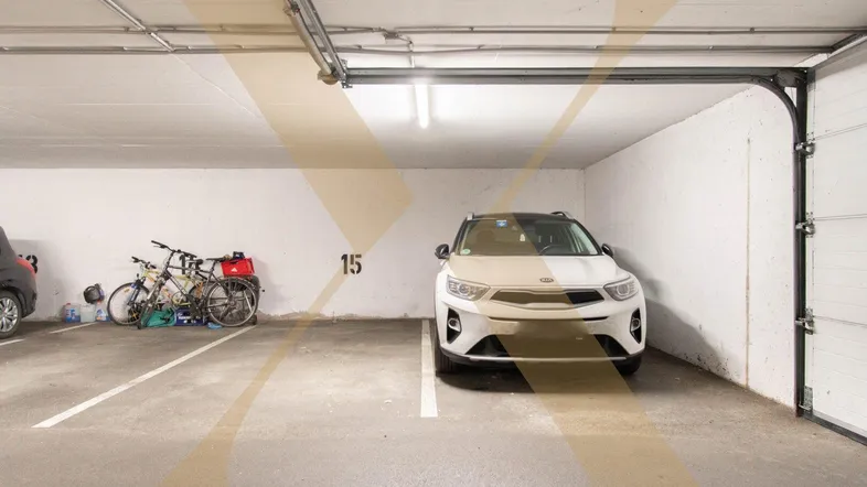 Heller Tiefgaragenstellplatz mit einem geparkten Auto und Fahrrädern, gut beleuchtet.