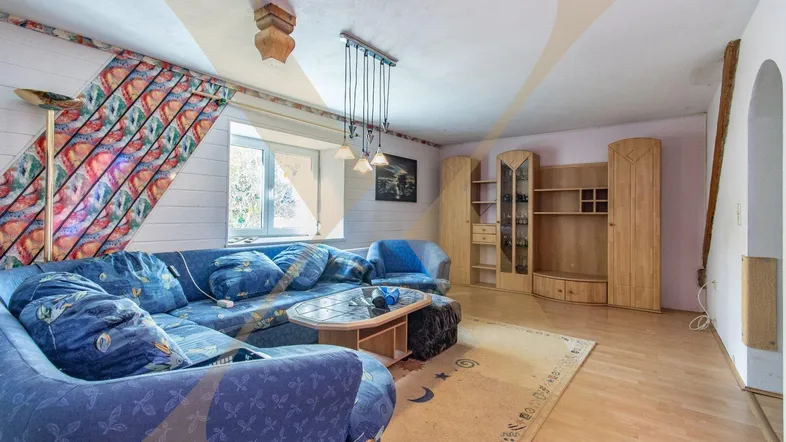 Helles Wohnzimmer mit blauer Eckcouch, Holzfußboden und rustikalen Möbeln.