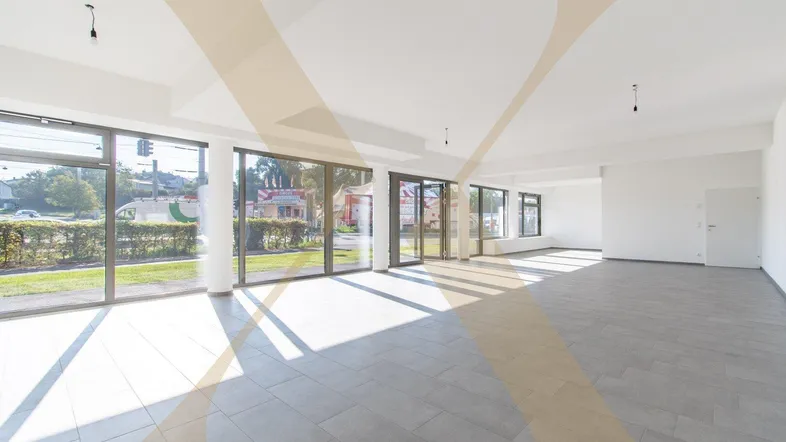 Heller, offener Gewerberaum mit großen Fensterfronten und modernem Fliesenboden, ideal für Ladenflächen.