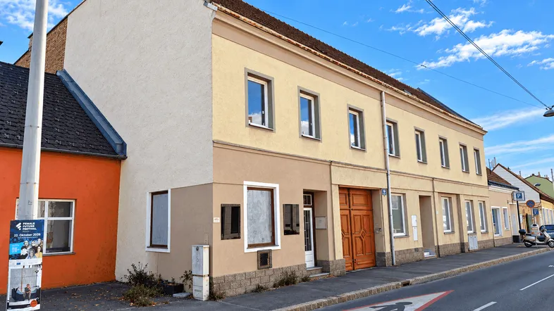 Mehrere Gebäude entlang einer Straße mit unterschiedlichen Fassadenfarben unter blauem Himmel.