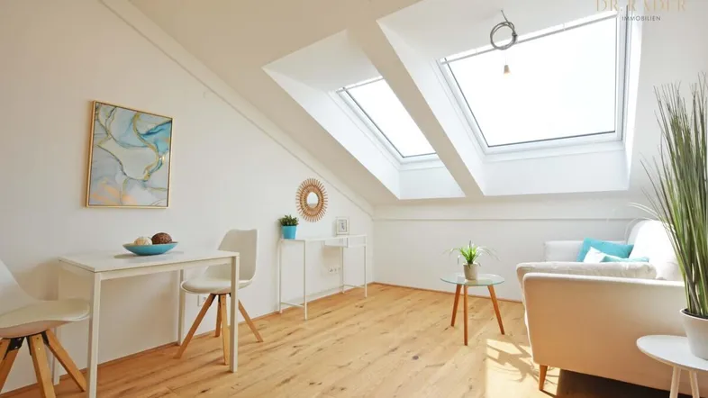 Helles Dachgeschoss-Wohnzimmer mit großen Dachfenstern, Holzboden und moderner Einrichtung.