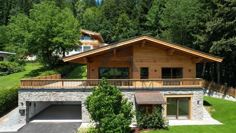 Modernes Holzhaus mit Steinfassade, integrierter Garage und umliegender Natur.