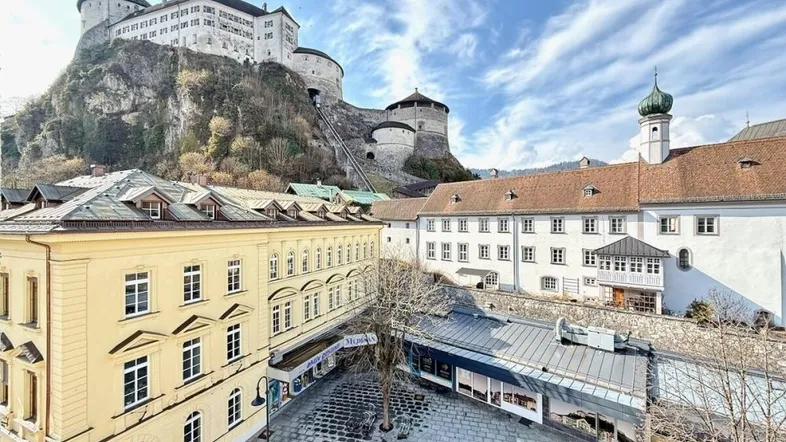 Blick auf die historische Stadt mit imposanter Burg auf dem Hügel und belebtem Platz.