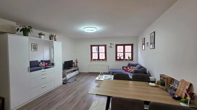 Geräumiger Wohn- und Essbereich mit Laminatboden, großem Kleiderschrank und gemütlicher Sitzecke.