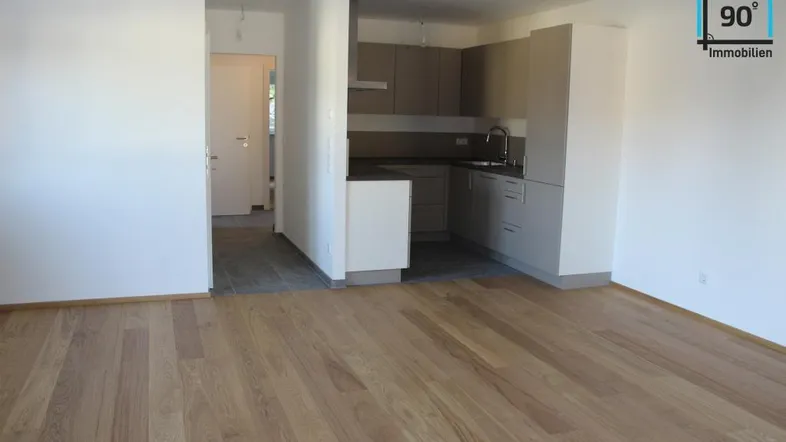Heller Wohnbereich mit neuem Parkettboden und integrierter Küchenzeile in modernem Design.