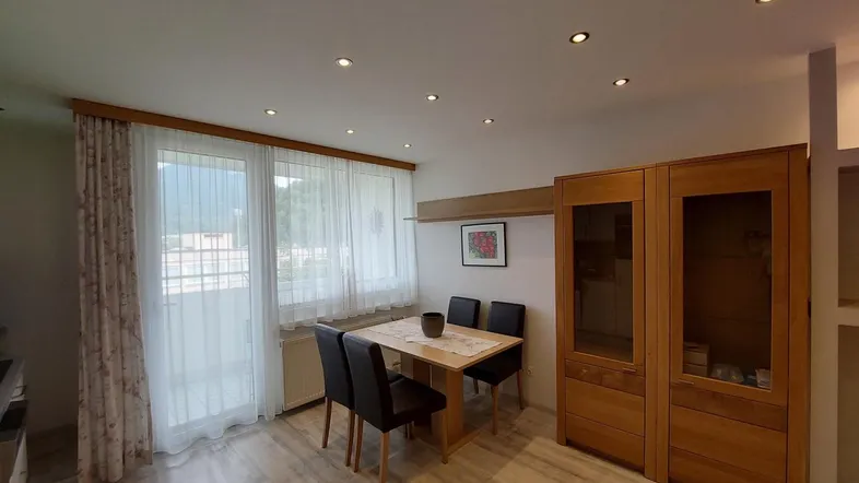 Heller Wohn-Essbereich mit Esstisch, Holzschränken und direktem Zugang zum Balkon.