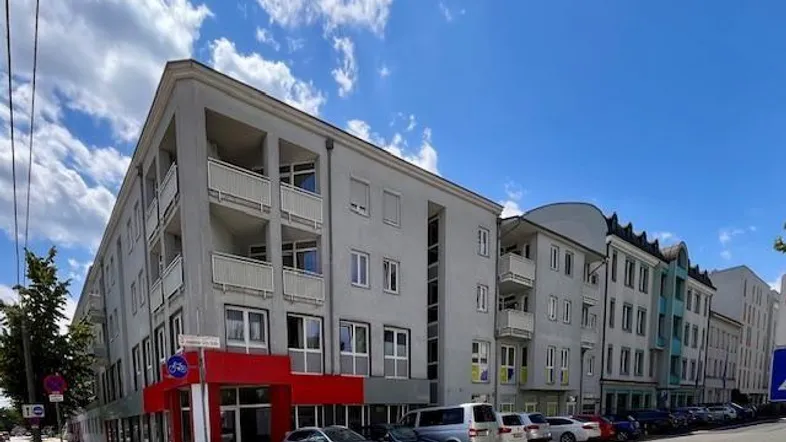 Modernes Mehrfamilienhaus mit Balkonen und Gewerbeflächen im Erdgeschoss an einer städtischen Straße.