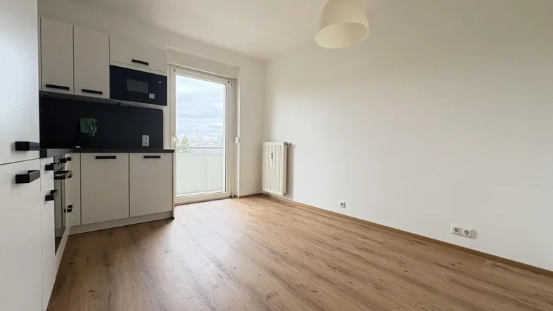Helle offene Wohnküche mit Laminatboden und Zugang zum Balkon, ideal für modernes Wohnen.