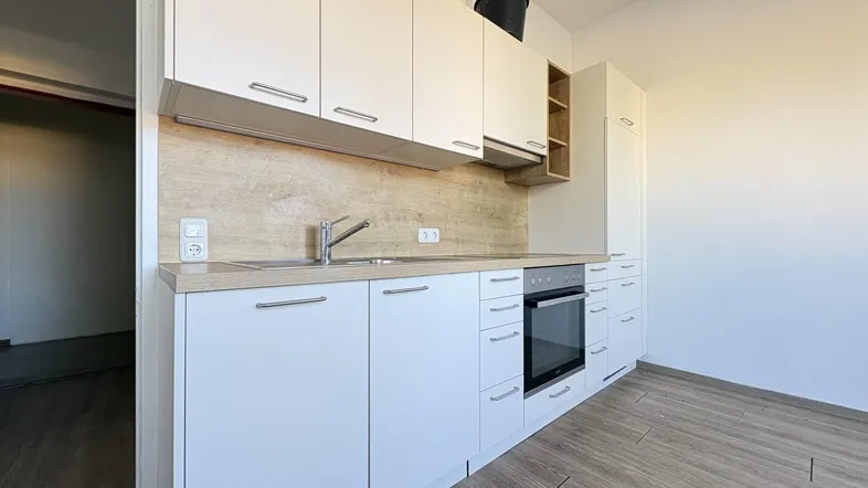 Moderne Einbauküche mit weißen Fronten, Holzoptik-Arbeitsplatte und integriertem Backofen.