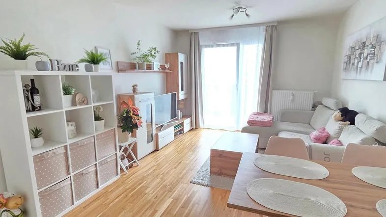 Helles Wohn- und Esszimmer mit Parkettboden, Sofa und Esstisch, ideal für gesellige Stunden.
