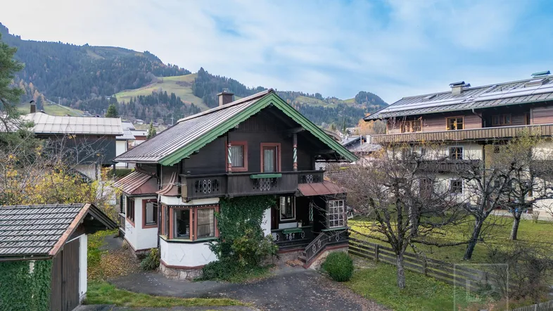 Traditionelles Haus im alpinen Stil mit Holzbalkonen und Blick auf die umliegenden Berge.