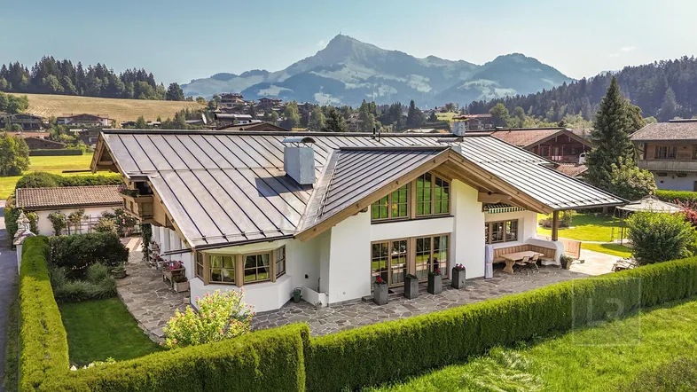 Großzügiges Anwesen mit traditioneller Architektur, umgeben von grüner Landschaft und beeindruckendem Bergblick.