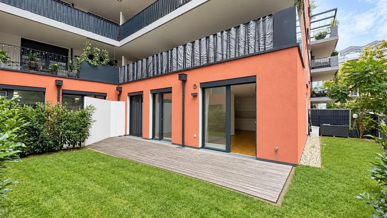 Private Gartenfläche mit Holzterrasse und Zugang zu den Wohnräumen im Erdgeschoss eines modernen Gebäudes.