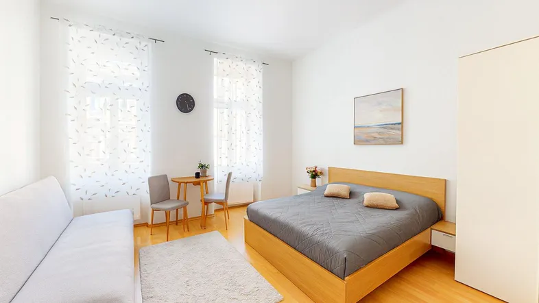 Helles Schlafzimmer mit Holzboden, einem bequemen Bett und einem Sofa für entspannte Stunden.