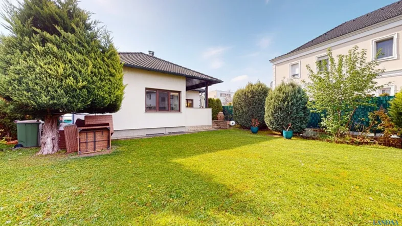 Großer, gepflegter Gartenbereich mit Rasenfläche und Bäumen neben dem Haus.