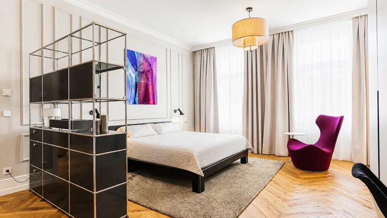 Helles Schlafzimmer mit Doppelbett, Fischgrätparkett und moderner Einrichtung.