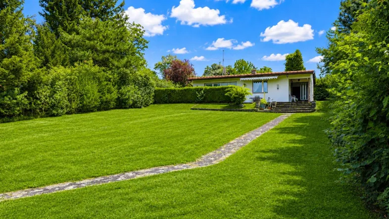 Großzügiger Garten mit weitläufiger Rasenfläche und einem charmanten Einfamilienhaus im Hintergrund.
