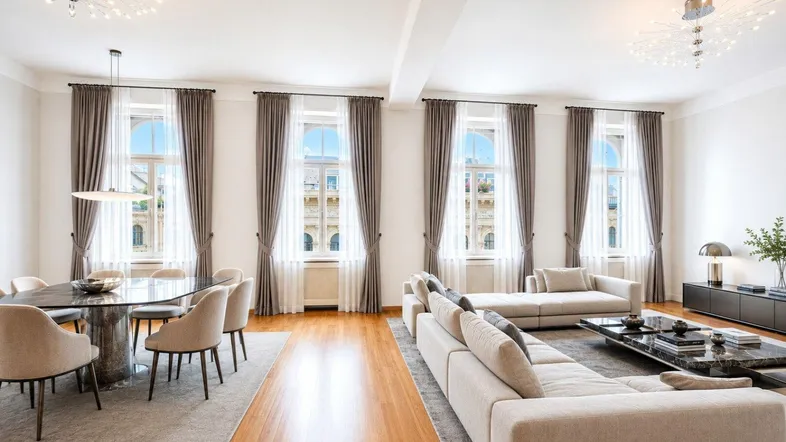 Helles, offenes Wohn- und Esszimmer mit hohen Decken, Parkettboden und großen Fenstern.