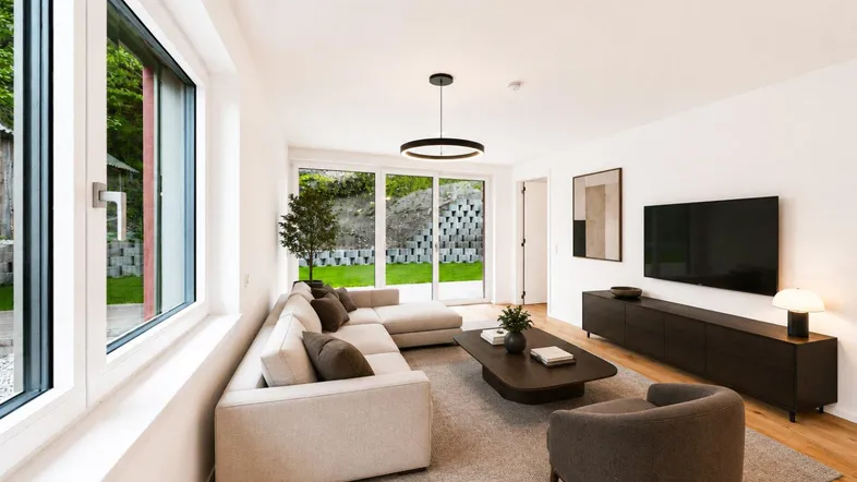 Modernes, helles Wohnzimmer mit bequemer Couch, Holzboden und Zugang zum Garten.