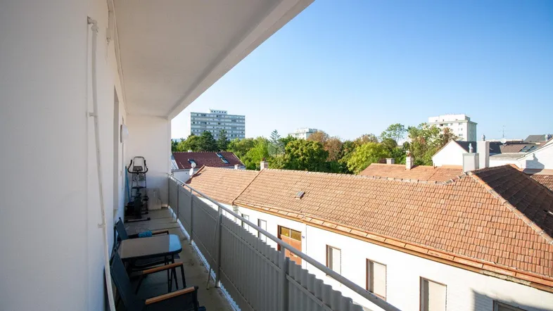 Geräumiger Balkon mit Sitzgelegenheiten und Blick über die Dächer der Stadt.