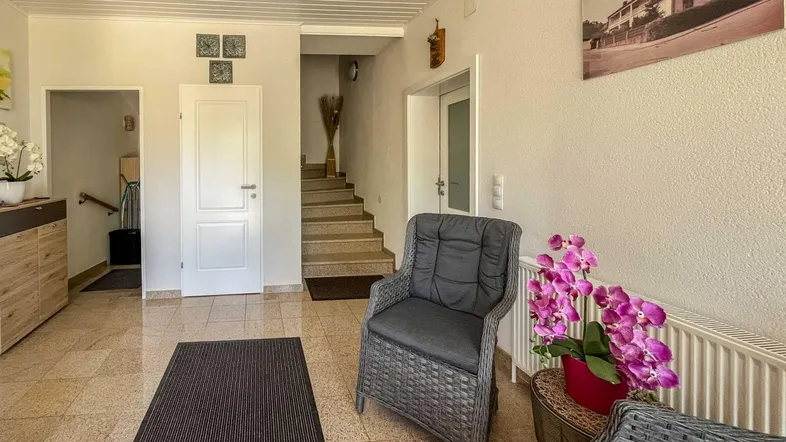 Heller Eingangsbereich mit gefliestem Boden, einer Treppe und gemütlicher Sitzgelegenheit.