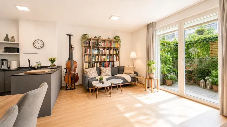 Helles, offenes Wohnzimmer mit integrierter Küche, Holzboden und Zugang zur Terrasse.