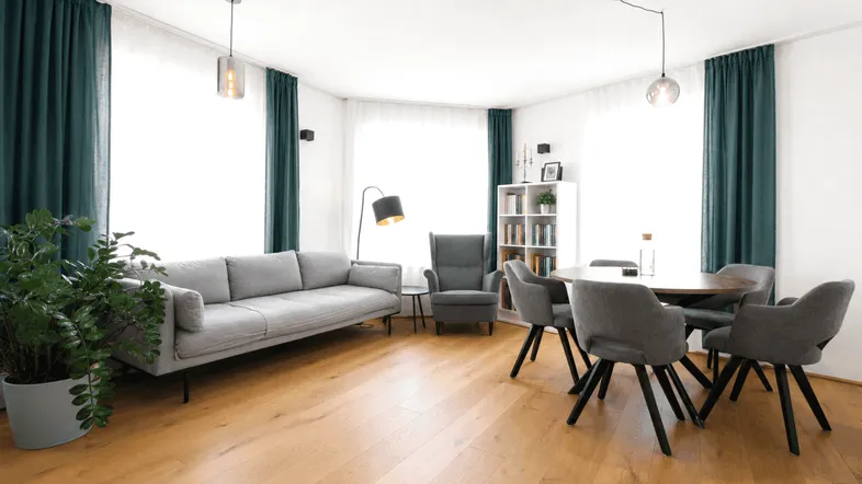 Helles Wohn- und Esszimmer mit Holzboden, bequemer Couch und modernem Esstisch für gesellige Stunden.