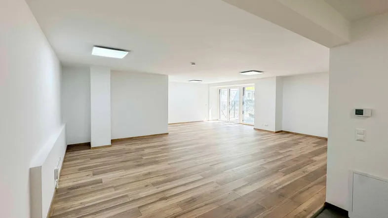 Geräumiger, heller Büroraum mit modernem Laminatboden und Zugang zu einer Terrasse.