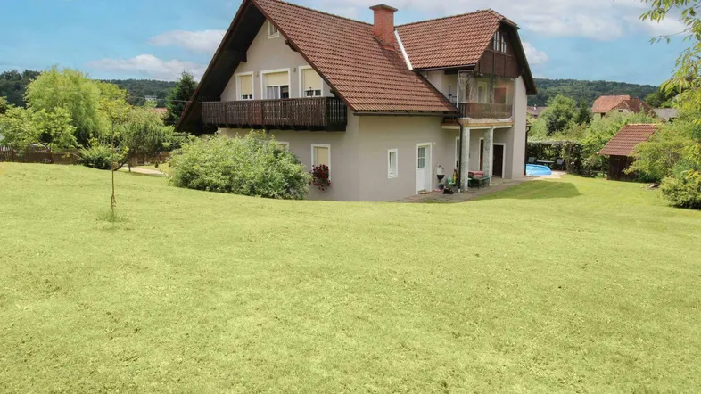 Freistehendes Haus mit großem Rasengarten und Blick auf die Landschaft unter blauem Himmel.
