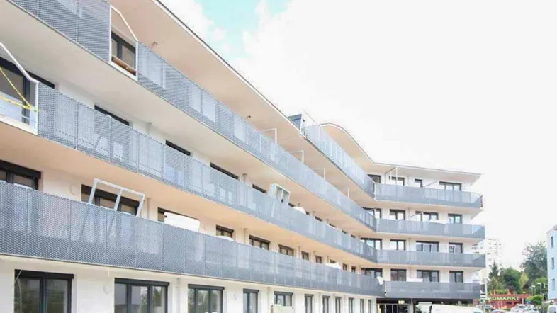 Moderne Wohnanlage mit mehreren Balkonen und einer hellen Fassade unter klarem Himmel.
