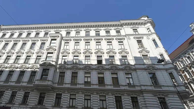 Die prächtige weiße Fassade des historischen Gebäudes mit vielen Fenstern und dekorativen Elementen unter blauem Himmel.