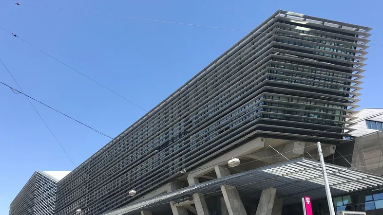 Moderne Bürogebäude-Fassade mit horizontalen Lamellen und großen Fensterfronten unter blauem Himmel.