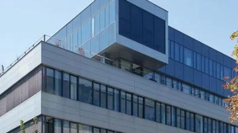 Modernes Bürogebäude mit Glasfassade und klaren Linien unter blauem Himmel.