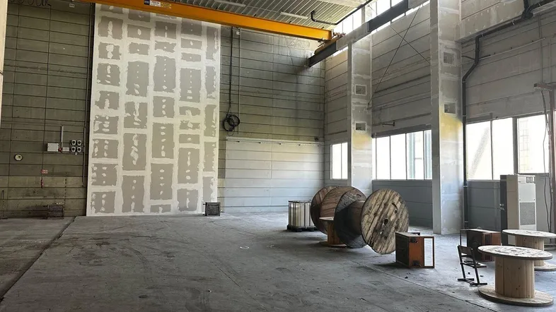 Große, leere Lagerhalle mit hohen Decken, Betonboden und sichtbaren Installationen, bereit zur Nutzung.
