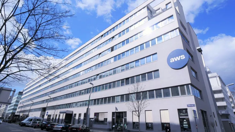 Modernes Bürogebäude mit vielen Fenstern und einer klaren Architektur unter blauem Himmel.