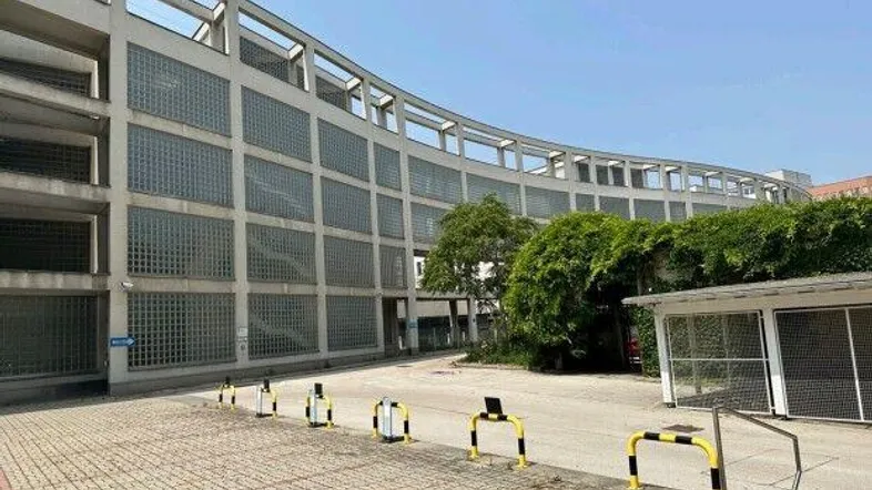 Modernes Parkhaus mit Glasbausteinfassade und Außenparkplätzen unter blauem Himmel.