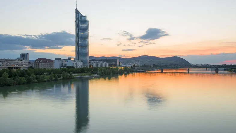 Panoramablick auf die Stadt bei Sonnenuntergang mit einem markanten Wolkenkratzer und Fluss.